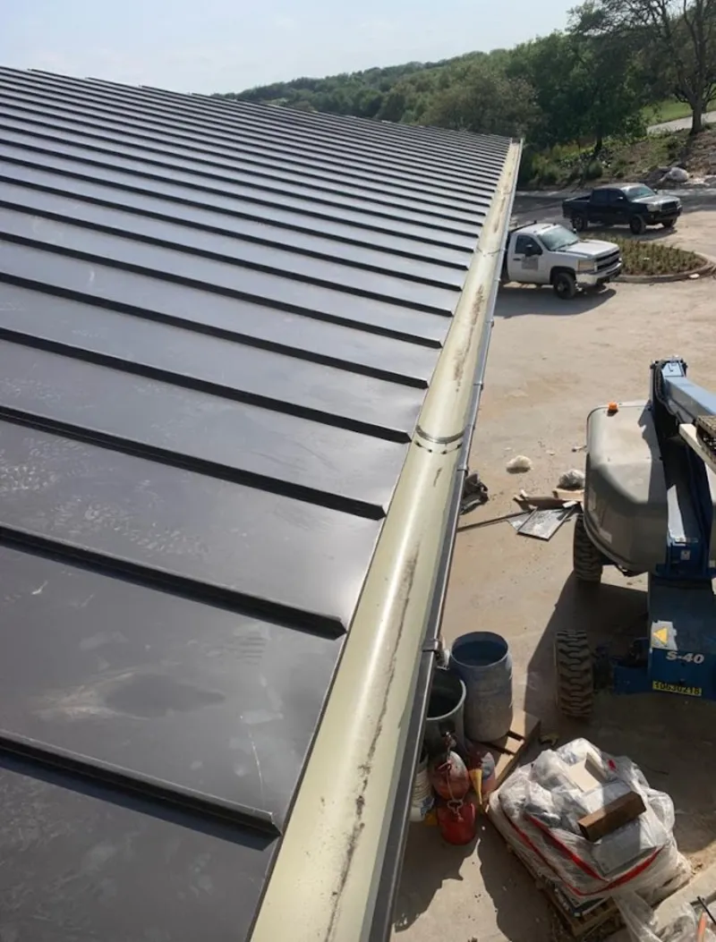 Standing seam panel and gutter detail on a metal roofing jobsite in Malden